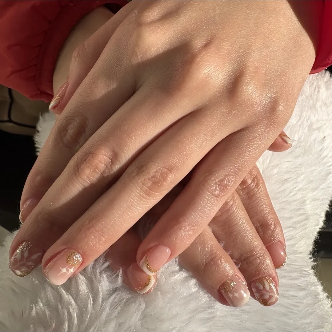 Nail art nude com folhas brancas e glitter dourado